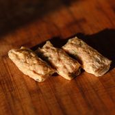 Three pale rolls with translucent wrappers, on a wooden board in low side light.