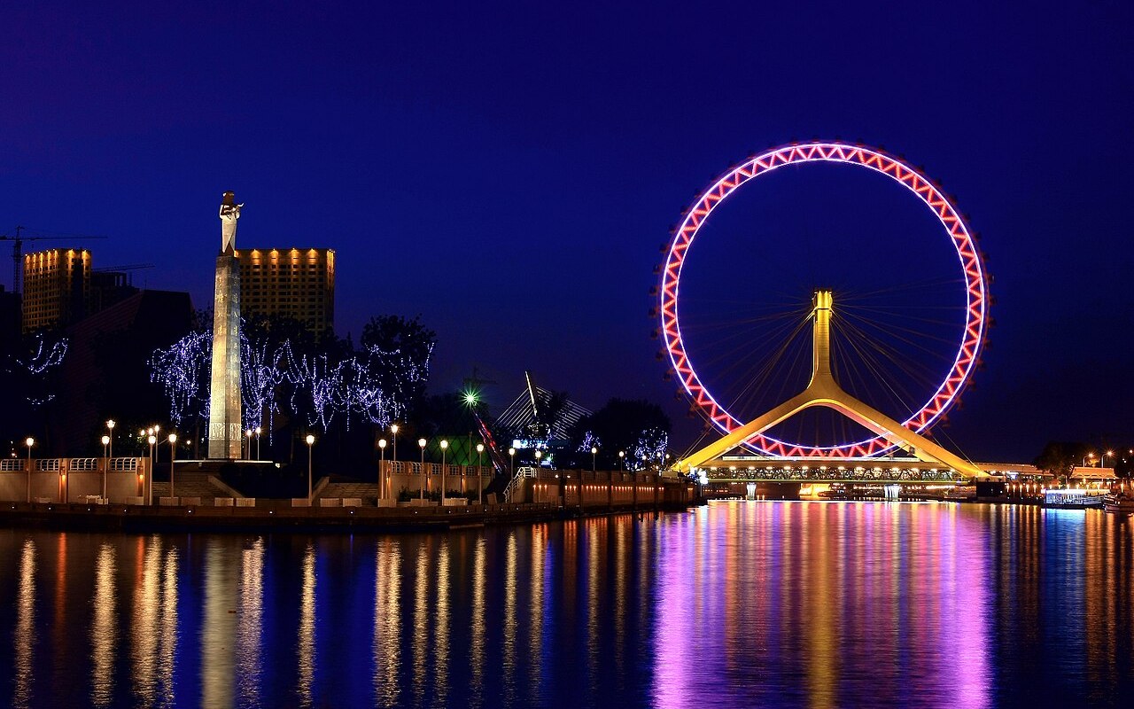 The Tianjin Eye ferris wheel lit pink over the Hai River at night